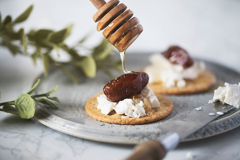 drizzling honey on cheese cracker